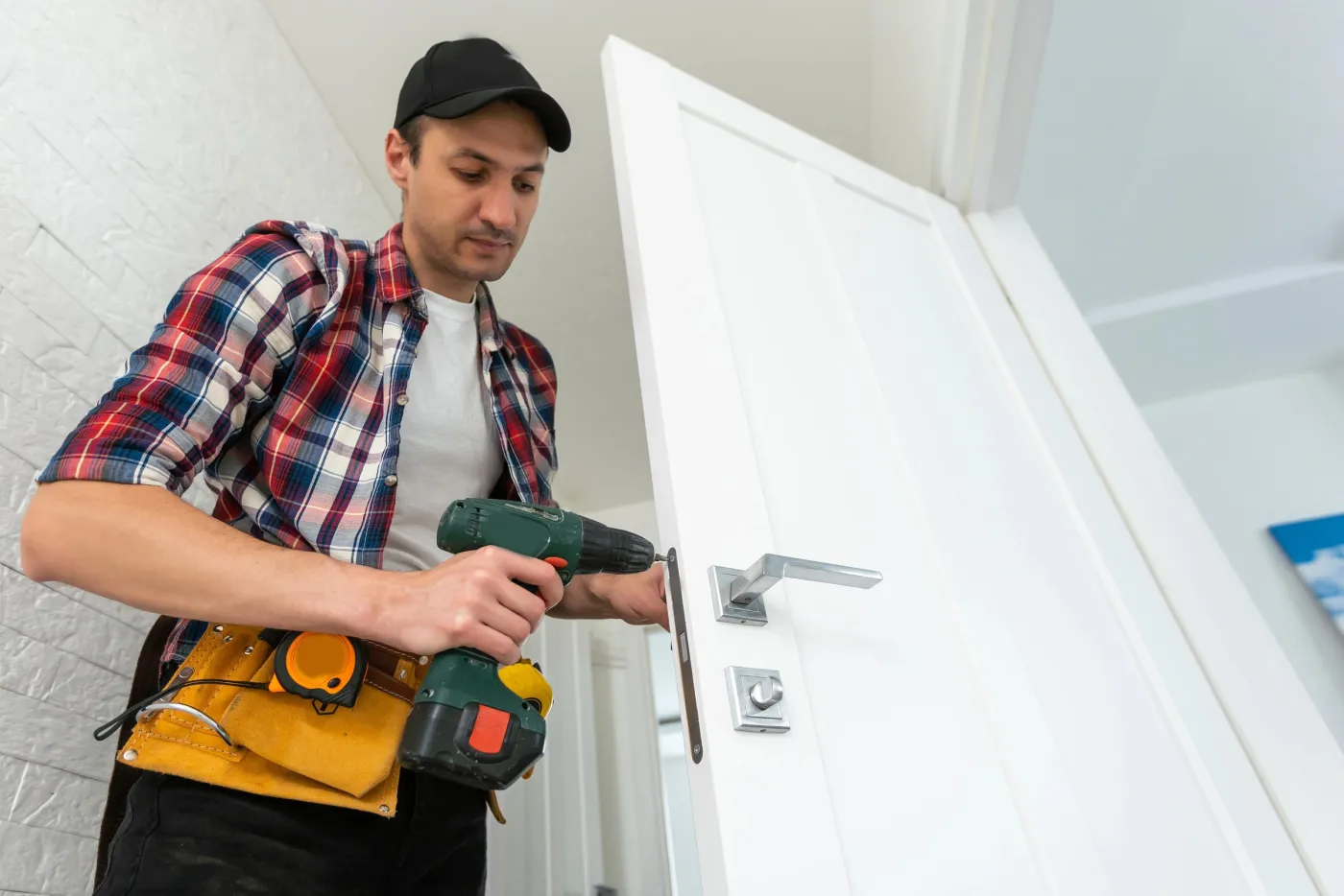 Artisan serrurier posant une poignée sur une porte d'entrée de pavillon à Carrières-sous-Poissy (78955)